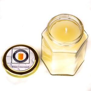 K&ouml;nnte beinhalten: Ein sechseckiges Glasgef&auml;&szlig; mit einem goldenen Deckel, das eine wei&szlig;e, unparf&uuml;mierte Kerze enth&auml;lt. Der Deckel tr&auml;gt ein Etikett mit der Aufschrift "Hubbardston Candle Company" und "White Unscented".