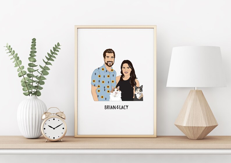 May include: A framed portrait featuring a couple and two cats. The man wears a blue shirt with sunflower patterns. The woman is in a black top. The portrait is labeled "BRIAN & LACY" in black text. The frame is gold.