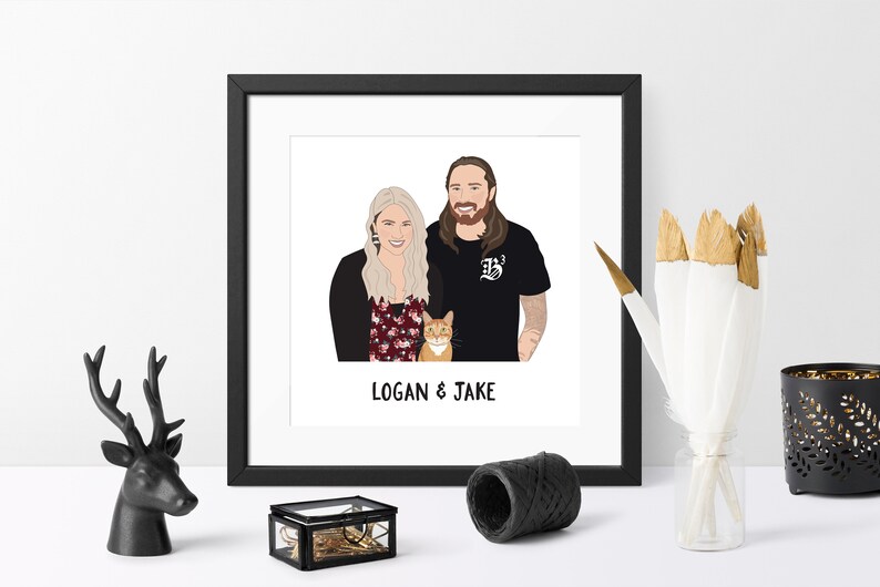 May include: A framed illustration featuring a couple and a cat, with the text "LOGAN & JAKE" below. The artwork is in a black frame, and the couple is depicted with blonde hair, a beard, and casual attire. The cat is orange.