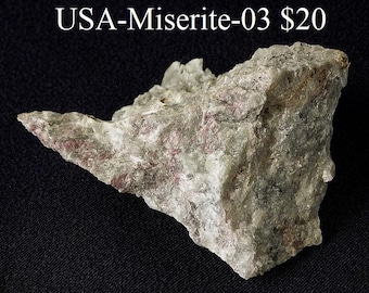 May include: A close-up of a gray and white rock with pink and red streaks. The rock is labeled "USA-Miserite-03 $20".