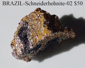 May include: A rough, multi-colored mineral specimen from Brazil. The rock has a textured surface with shades of brown, gold, and black, with sparkling inclusions. The text "BRAZIL-Schneiderhohnite-02" is visible at the top.