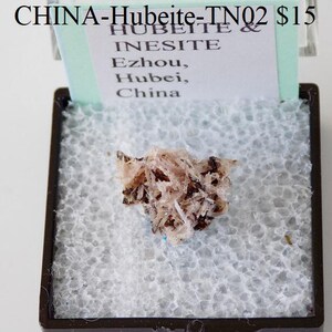 May include: A small, pink and brown mineral specimen labeled "CHINA-Hubeite-TN02 $15 HUBEITE & INESITE Ezhou, Hubei, China"