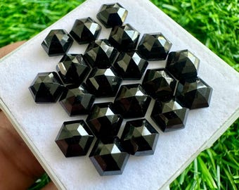 May include: A collection of 20 black faceted gemstones in a square white box. The gemstones are arranged in a pattern and are all the same size and shape.