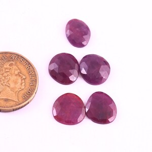 Puede incluir: Cuatro piedras preciosas de rubí facetadas de diferentes tamaños y formas. Las piedras preciosas son de color rojo intenso y tienen un acabado pulido.