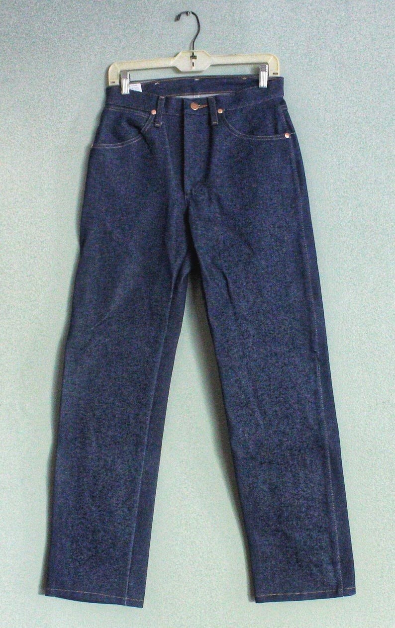 Puede incluir: Un par de pantalones vaqueros de mezclilla azul oscuro con un corte recto cl&aacute;sico. Los pantalones tienen cierre de bot&oacute;n y trabillas para cintur&oacute;n.