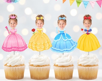 May include: Four cupcake toppers featuring cartoon princess bodies with a child's face on each. The princesses wear pink, yellow, blue, and yellow dresses with accessories like a crown, rose, and apple. Each topper is mounted on a white stick.
