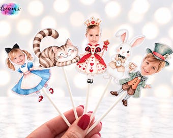 May include: A set of five decorative paper cake toppers featuring illustrations of characters with photographic faces. The set includes a girl in a blue dress, a striped cat, a queen with a crown, a white rabbit, and a boy in a top hat.