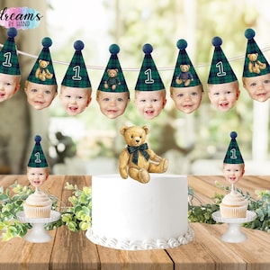 Puede incluir: Un set de decoraci&oacute;n de fiesta con una guirnalda de caras de beb&eacute; con gorros de fiesta de cuadros verdes y el n&uacute;mero 1, un adorno de oso de peluche para tarta y dos adornos para cupcakes con caras de beb&eacute; y el logo Dreams by Hand.