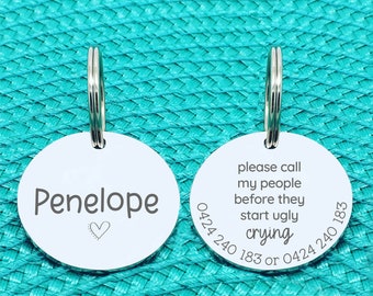 May include: Two silver dog tags with a key ring. The tag on the left says "Penelope" with a small heart. The tag on the right says "Please call my people before they start ugly crying 0424 240 183 or 0424 240 183".