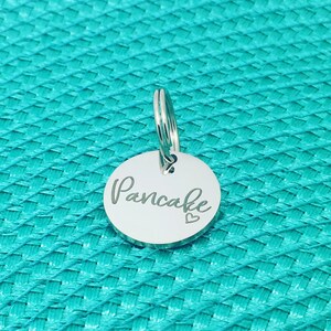 May include: Silver key chain with a round tag that says "Pancake" with a small heart symbol.