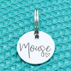 May include: Silver pet tag with the name "Mouse" engraved in a cursive font with a small heart symbol.