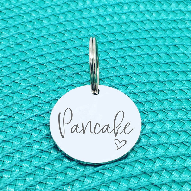 May include: A silver keychain with a round tag that says "Pancake" with a small heart symbol.
