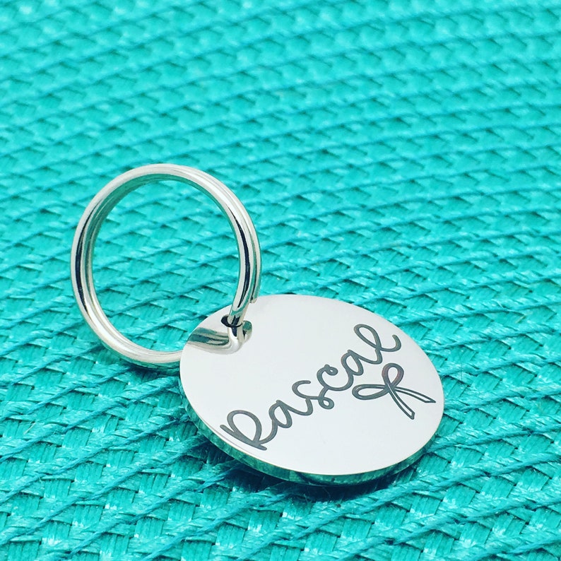 May include: Silver key chain with a round tag engraved with the name "Pascal" in cursive script.