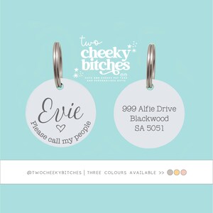May include: Two round silver-toned metal pet tags with split rings. The left tag features the name Evie, a heart icon, and the text Please call my people. The right tag displays the address 999 Alfie Drive, Blackwood, SA 5051. The brand logo reads two cheeky bitches.