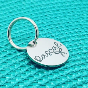 May include: Silver key chain with a round tag engraved with the name "Pascal" and a small scissor design.