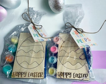 May include: Two Easter-themed craft kits with wooden egg-shaped canvases, paint pots, paintbrushes, and a tag that reads "Happy Easter To My Favorite Peeps".