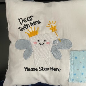 May include: White pillow with embroidered tooth fairy design. The tooth fairy is a white tooth with a yellow crown, wings, and a wand. The text reads "Dear Tooth Fairy Please Stop Here".