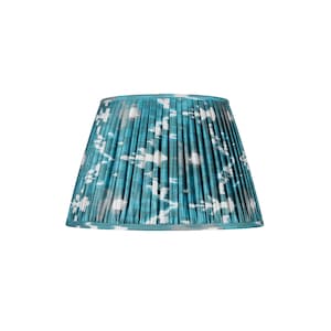 Könnte beinhalten: Ein blaugrüner Lampenschirm mit einem weißen und grauen Ikat-Muster. Der Lampenschirm ist gefaltet und hat einen weißen Saum.