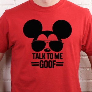 May include: Red t-shirt featuring a black graphic of Mickey Mouse wearing sunglasses, with the text "TALK TO ME GOOF" in black. The design includes two horizontal lines above and below the word "GOOF".