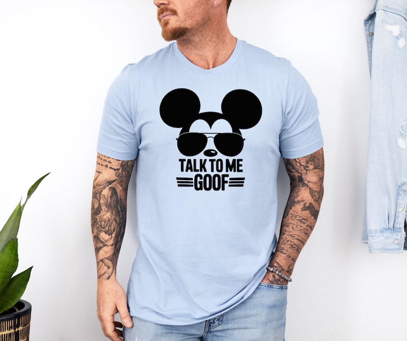 Puede incluir: Camiseta azul claro con un gr&aacute;fico negro de Mickey Mouse con gafas de sol y el texto "TALK TO ME GOOF". La camiseta de manga corta est&aacute; hecha de un material suave.