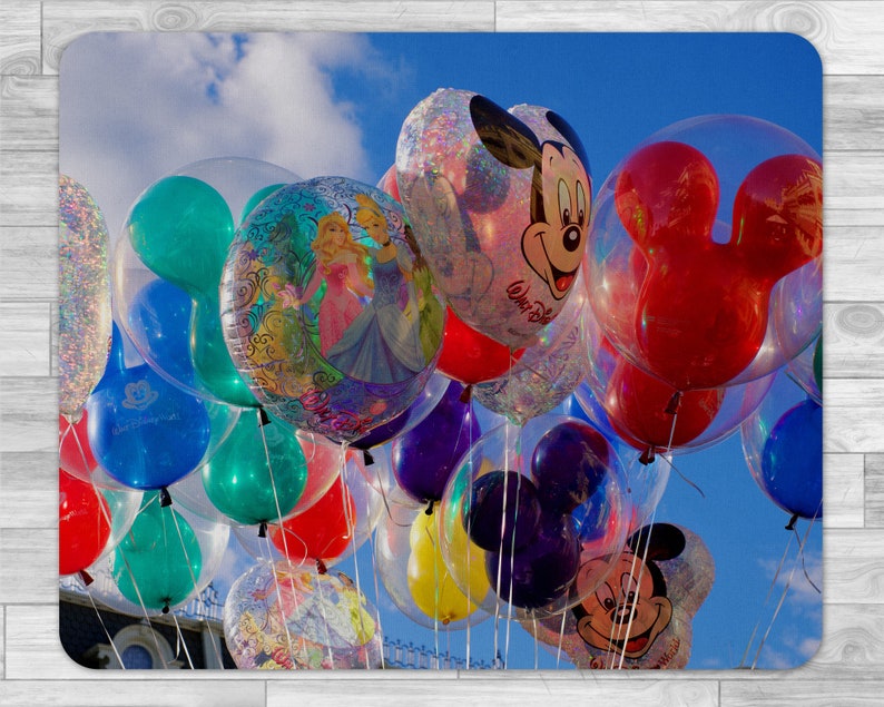Peut inclure: Une collection de ballons color&eacute;s avec diff&eacute;rents personnages Disney, dont Mickey Mouse, Minnie Mouse et des princesses, sur fond de ciel bleu avec des nuages blancs.