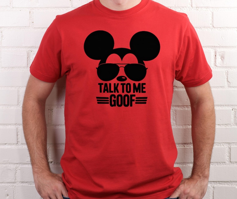 Puede incluir: Camiseta roja con un gr&aacute;fico negro de Mickey Mouse con gafas de sol. El texto "TALK TO ME GOOF" est&aacute; impreso en negro debajo. La camiseta es de manga corta.