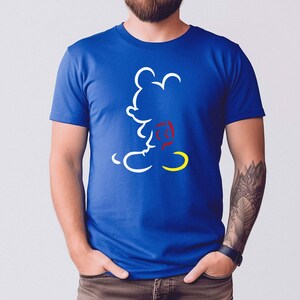 May include: Royal blue t-shirt featuring a white outline of Mickey Mouse with a red and yellow accent. The graphic is a minimalist design of the iconic character. The shirt is a classic crew neck style.