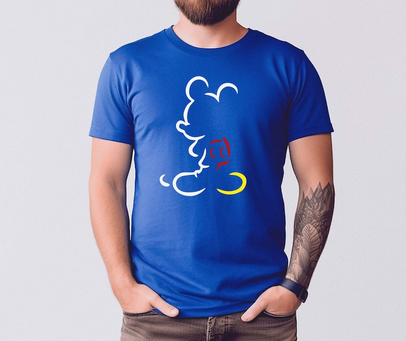 May include: Royal blue t-shirt featuring a white outline of Mickey Mouse with a red and yellow accent. The graphic is a minimalist design of the iconic character. The shirt is a classic crew neck style.