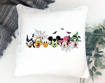 May include: White square pillow featuring a Halloween-themed design with cartoon characters. The design includes Donald Duck, Pluto, Daisy Duck, Mickey Mouse, Minnie Mouse, and Goofy, along with spiderwebs and bats.