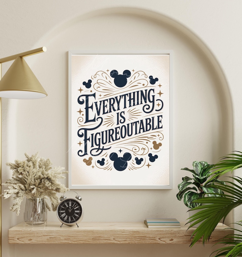 May include: Framed art print with the text "Everything is Figureoutable" in a decorative font, surrounded by Mickey Mouse silhouettes and stars. The artwork is in a white frame and is displayed on a wooden shelf with a clock and dried flowers.