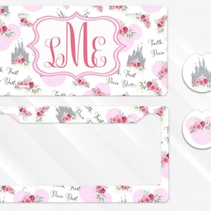 May include: A license plate, license plate frame, and two car coasters with a floral and castle design. The license plate and frame have a white background with pink polka dots, flowers, and a castle. The coasters have a similar design.