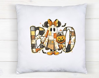 May include: White square pillow with a Halloween-themed design. The design features the word "BOO" in a patchwork style, with a ghost character holding a jack-o'-lantern. The ghost has a bow and mouse ears. Bats and stars complete the design.