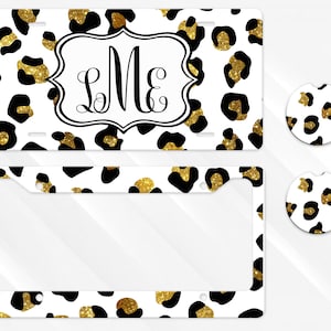 May include: A white license plate, license plate frame, and two car coasters with a black and gold leopard print design. The license plate has a monogram with the letters "LMe".