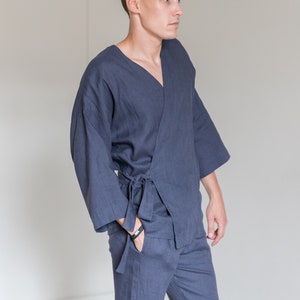 Op de afbeelding: Een donkerblauwe linnen wikkeltop en bijpassende broek. De top heeft een V-hals en een strikband. De broek heeft een rechte pijp.