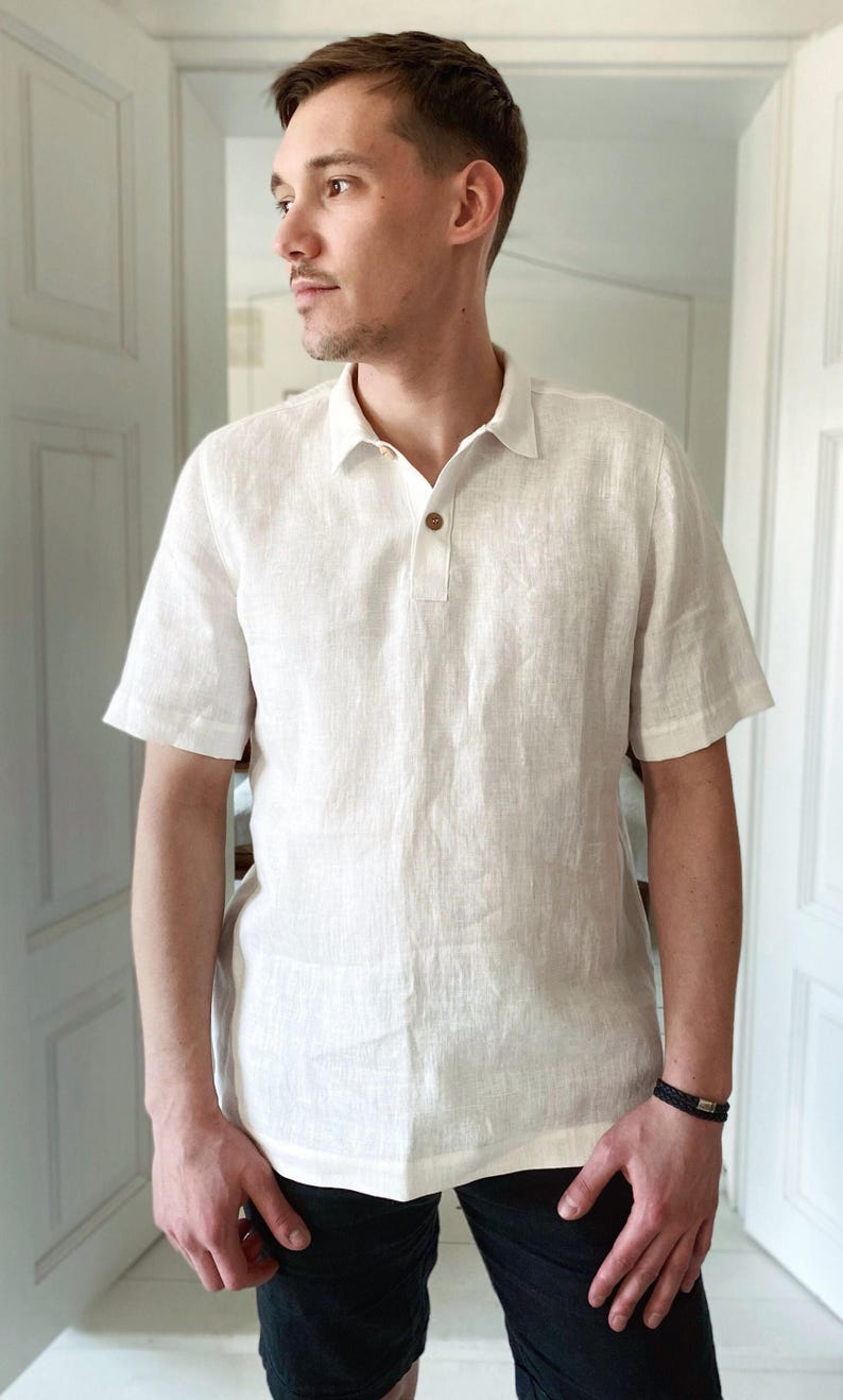 May include: A white linen short-sleeved shirt with a button-down collar and a single button closure. The shirt is made of a lightweight, breathable fabric and has a relaxed fit.
