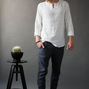 A man standing in a studio wearing classic linen pants with a slightly tapered fit and a casual yet polished look