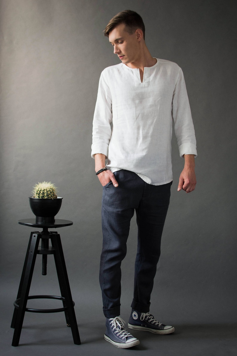 A man standing in a studio wearing classic linen pants with a slightly tapered fit and a casual yet polished look