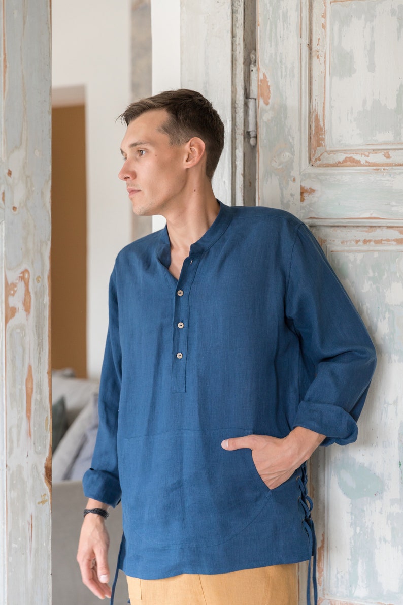 Op de afbeelding: Een blauw linnen overhemd met een mandarijnkraag en lange mouwen. Het overhemd heeft een enkele knoopsluiting en een zak aan de linkerkant. Het overhemd is aan de zijkant vastgebonden met een touwtje.