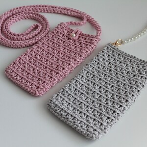 May include: Two crocheted phone pouches with straps. One pouch is pink with a crocheted strap and the other is gray with a pearl strap.