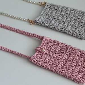 May include: Two crocheted phone pouches, one in pink and one in gray, with pearl and chain straps.