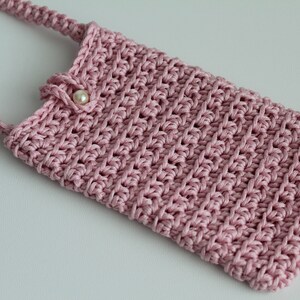May include: A pink crocheted phone case with a pearl button and a long strap.