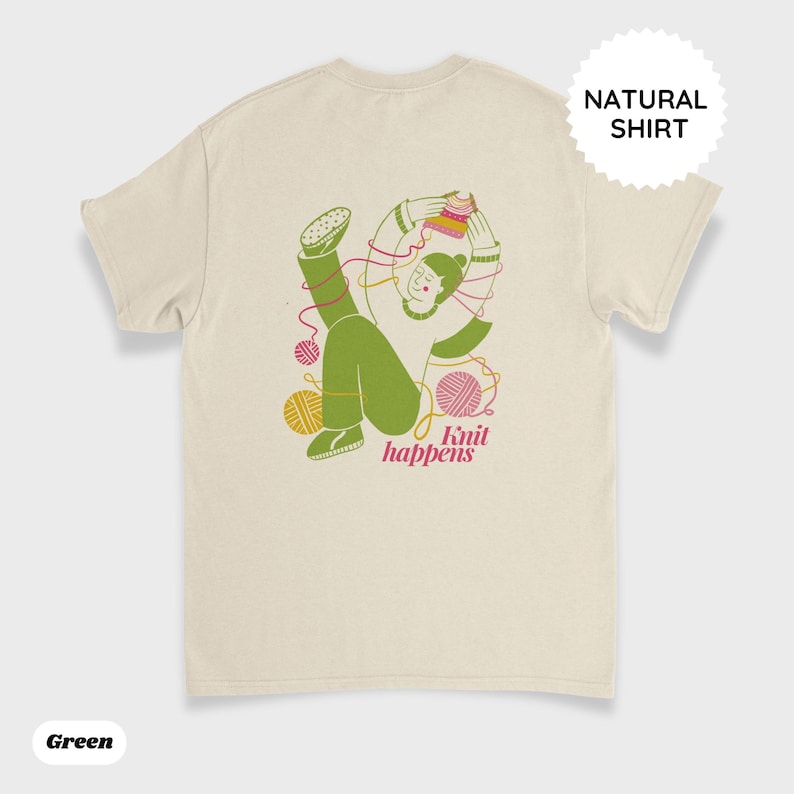 May include: A natural-colored t-shirt with a green illustration of a person knitting, surrounded by yarn balls and the text "Knit happens" in pink. The shirt also has a "NATURAL SHIRT" label.