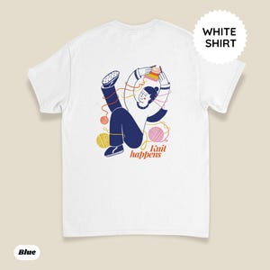 May include: White t-shirt with a graphic illustration of a person knitting, surrounded by yarn balls and the text "Knit happens." The design features blue, yellow, pink, and orange colors. A white circle with the words "WHITE SHIRT" is in the upper right corner.