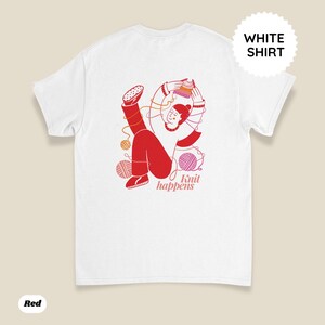 May include: White t-shirt with a red illustration of a person knitting, surrounded by yarn balls. The text "Knit happens" is printed in a pink font. A white circle with the words "WHITE SHIRT" is on the top right.
