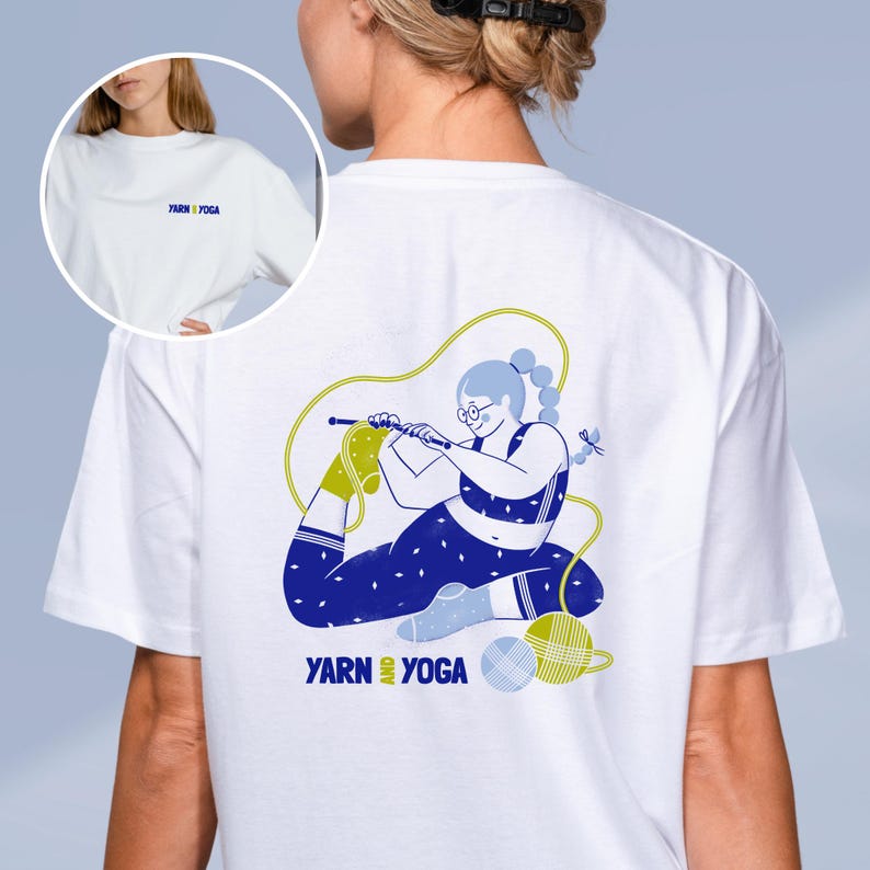 Op de afbeelding: Wit T-shirt met een blauw en geel ontwerp van een persoon die breit in een yoga pose. De tekst "YARN & YOGA" staat op de voor- en achterkant. Het shirt heeft een ronde hals en korte mouwen.