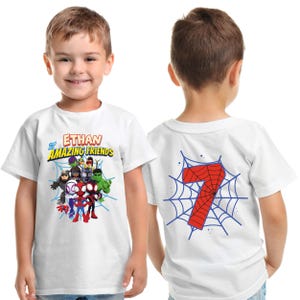 Puede incluir: Camiseta blanca con un grupo de superh&eacute;roes de dibujos animados y el texto "Ethan Amazing Friends" en la parte delantera. La parte trasera muestra el n&uacute;mero 7 rojo en un dise&ntilde;o de telara&ntilde;a azul. Un ni&ntilde;o lleva la camiseta.
