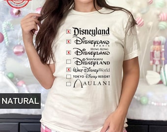 May include: A white t-shirt with a black graphic of a checklist with the names of different Disney parks, including Disneyland Resort, Disneyland Paris, Disneyland Hong Kong, Disneyland Shanghai, Walt Disney World, Tokyo Disney Resort, and Aulani.