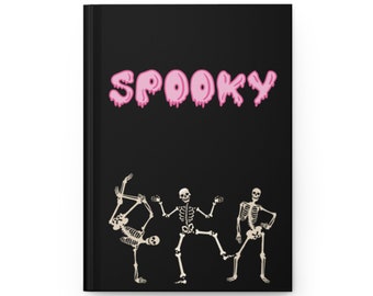 May include: A black notebook with the word "SPOOKY" in pink dripping letters. Three skeletons are dancing on the cover.