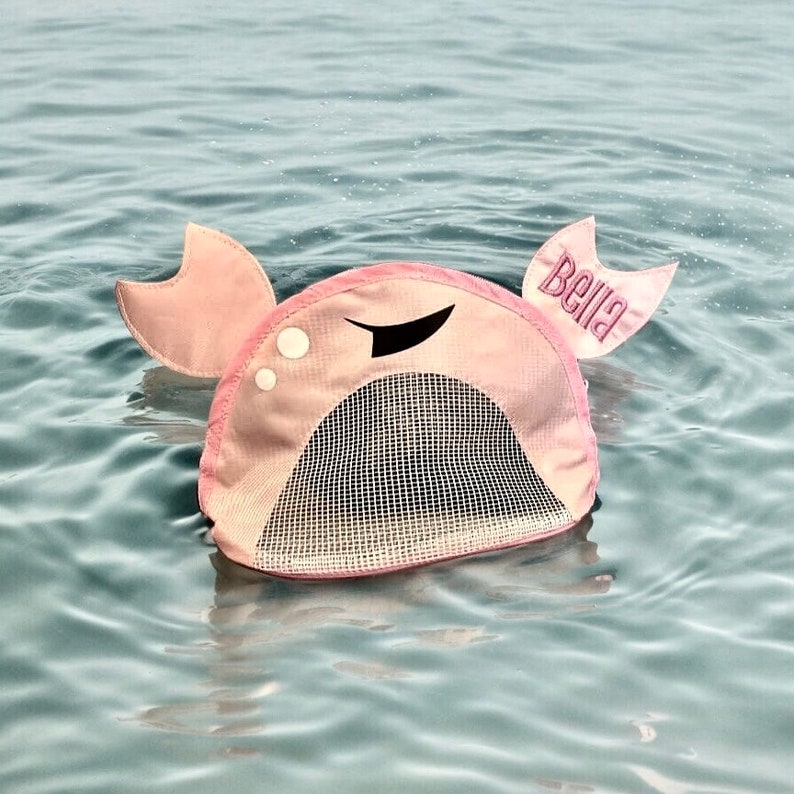 May include: Pink crab-shaped pool float with a mesh net in the center and the name "Bella" embroidered on one of the crab claws.
