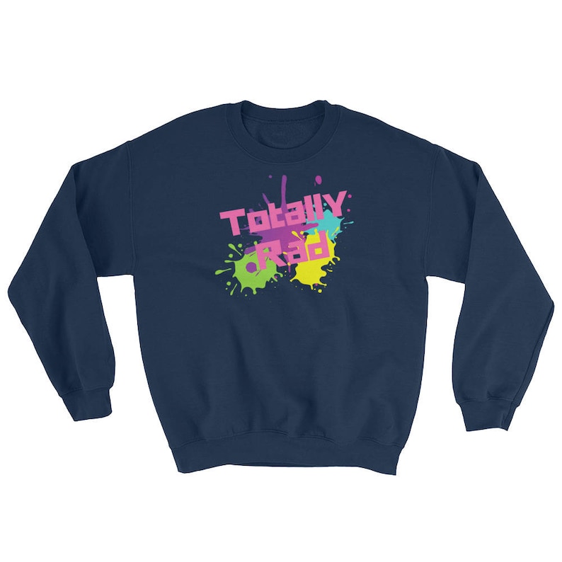 May include: Navy blue sweatshirt with the text "Totally Rad" in pink, purple, and yellow, with colorful paint splatter accents. A casual, retro-themed garment.